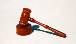 Wooden judges gavel and block on a white table background.