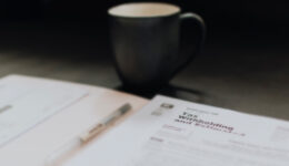 Blurry background of a black coffee cup and a file folder with tax withholding documents.