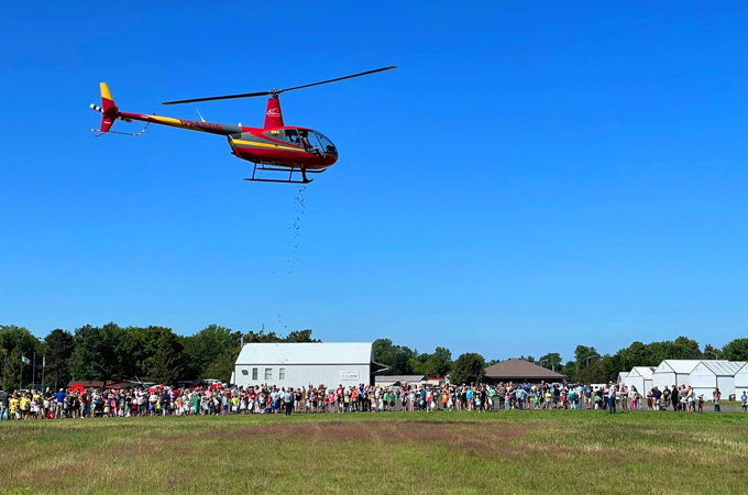 Red helicopter dropping candy for kids at the municipal airport at the Village of Boyceville, Wisconsin during Pickle Fest.