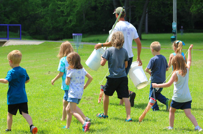 Elementary teacher and some students walk to Tiffany Creek in the Village of Boyceville, Wisconsin while carrying buckets and nets for a science experiment.